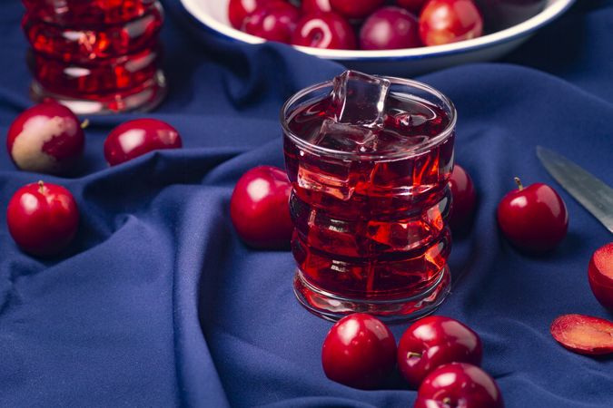Red beverage near fresh fruits on cloth