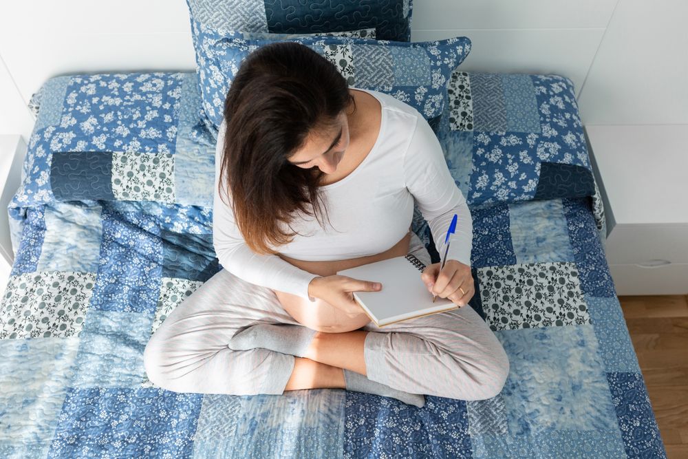 Pregnant woman taking notes in notepad