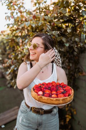 cheerful woman holding a delicious strawberry pie