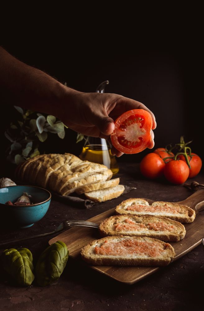 Crop person pouring tomato on toasts