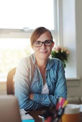 Confident female entrepreneur sitting at her desk in her bright home office, vertical