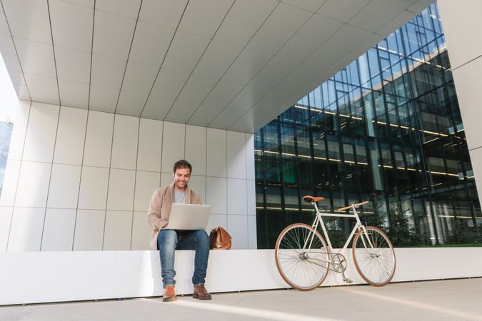 Cheerful businessman using laptop on street
