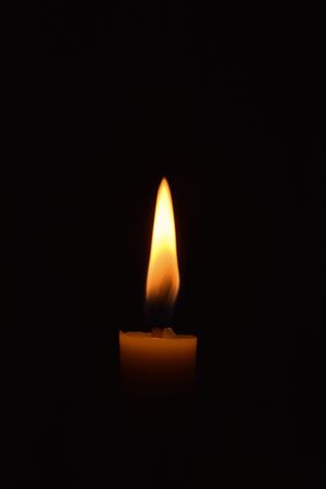 Side view of candle burning in the dark with copy space