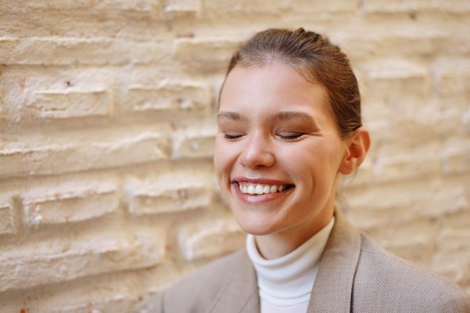 A Woman Smiling Joyfully Against a Textured Wall, Radiating Warmth and Happiness