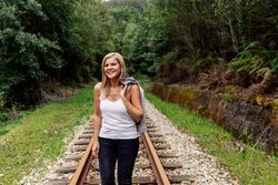 Woman walking along railway though greenery part of road