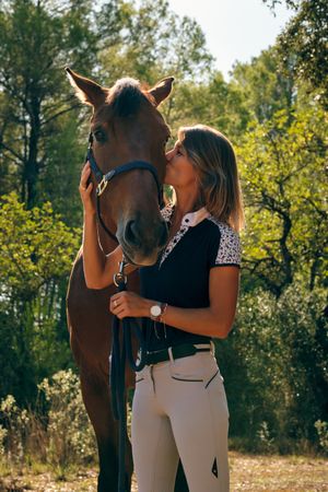 Horsewoman kissing horse in forest