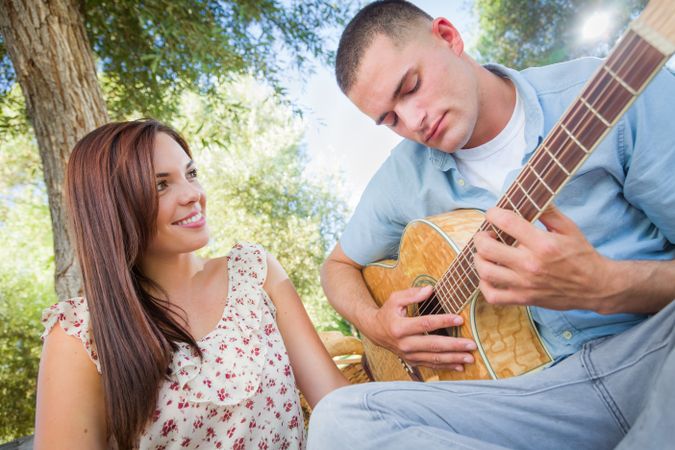 Young Man Playing Guitar for His Girlfriend in the Park.