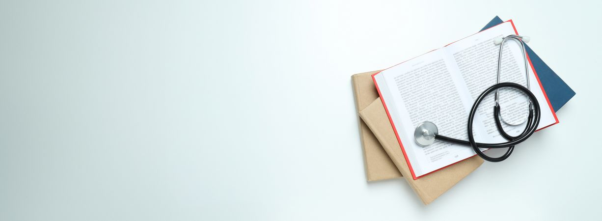Stethoscope and books on light background, space for text