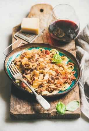 Pasta dinner with minced meat, cheese and red wine on wooden board