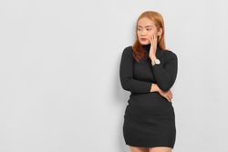 Stressed Asian woman with hand resting on face lost in thought