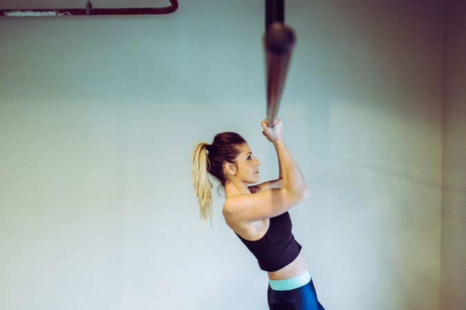 Young woman doing pull ups in gym