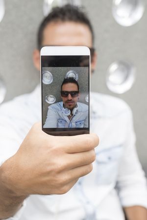 Phone screen of male in sunglasses taking picture of himself