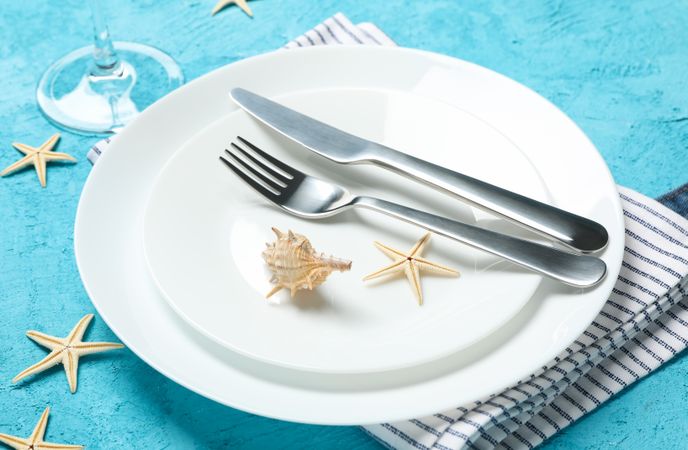 Table setting with seashells and starfishes on turquoise background, close up