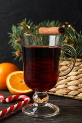 Glass of tasty mulled wine on decorated wooden background, space for text