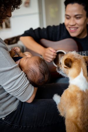 Woman playing acoustic guitar for baby, partner and pets, vertical