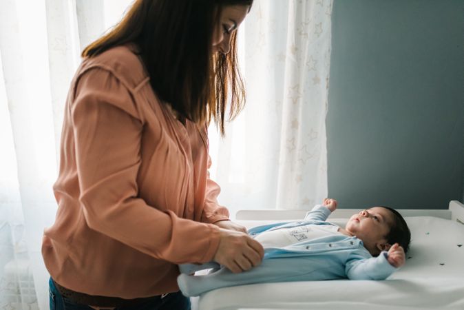 Woman dressing adorable little baby