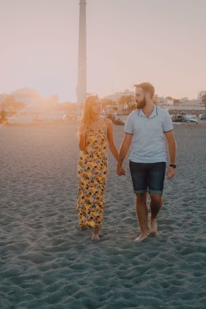 Lovely couple walking holding hands on sandy beach