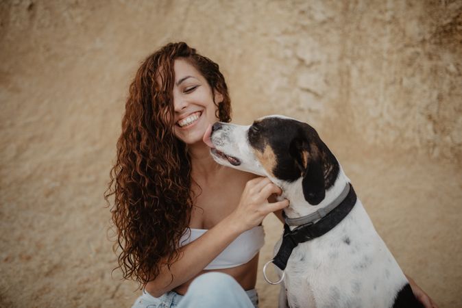 Dog licking face of cheerful woman