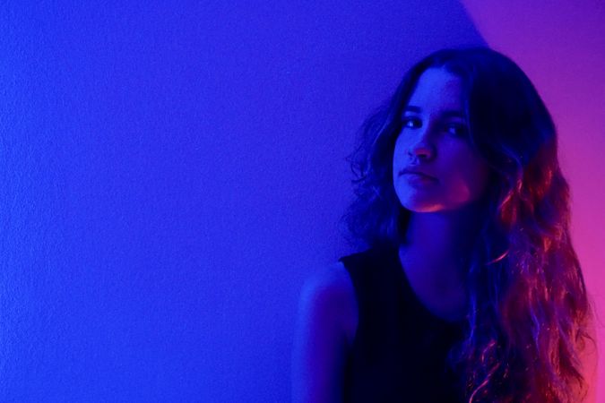 Portrait of pensive teenage girl in purple lit studio