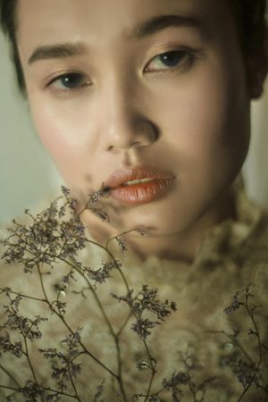Portrait of east Asian woman beside dried plant