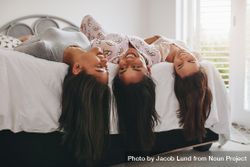 Young women lying on edge of bed with their hair hanging down 5ljdMb