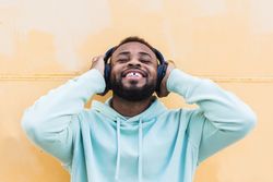 Optimistic Black hipster listening to music with headphones