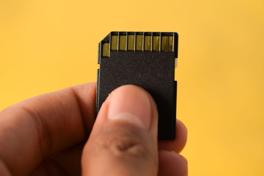 Close up of SD card in hand with yellow background and space for text
