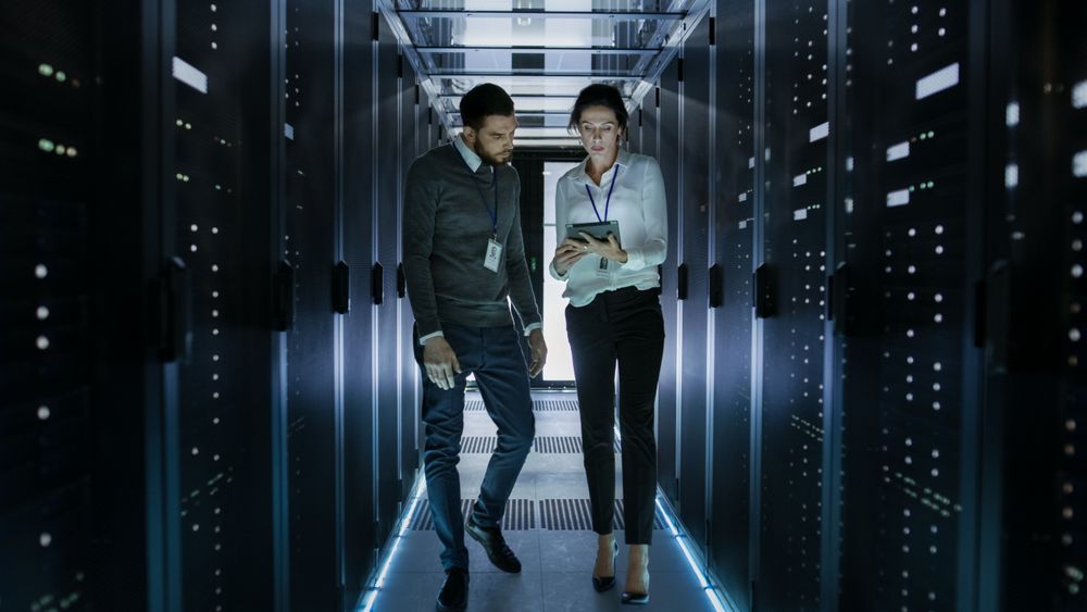 Male and Female Server Technicians Working in Data Center.