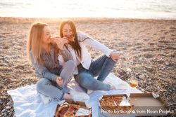 Two women eating pizza on seashore 4mBpdb