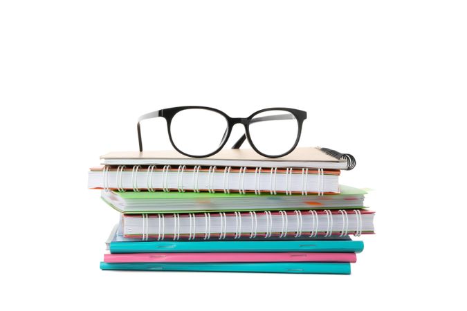 Notebooks topped with glasses in blank space