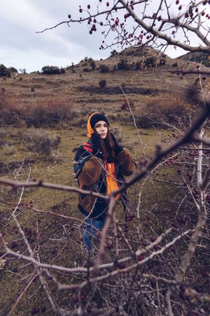 Hiker with backpack standing along pathway in autumn forest