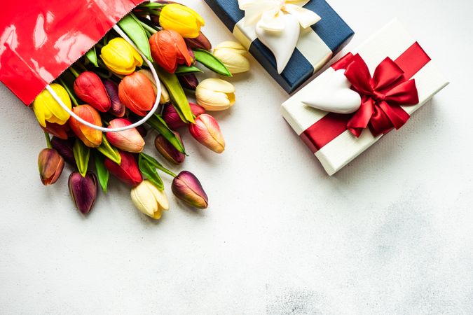 Tulips in shopping bag with presents on grey counter