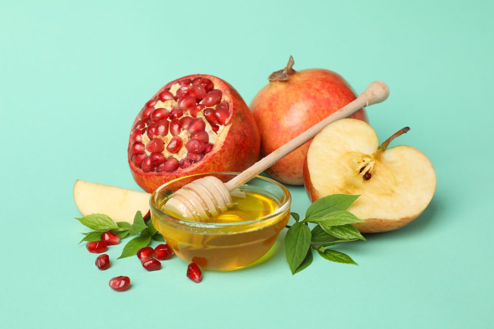 Open pomegranate, apple half, and honey in mint room