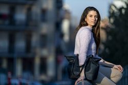 Woman with handbag sitting on bridge outside at dusk