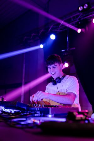 Happy Young DJ mixing in a disco with neon lights