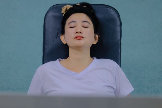 Her eyes are closed and her head is leaning on the back of the chair