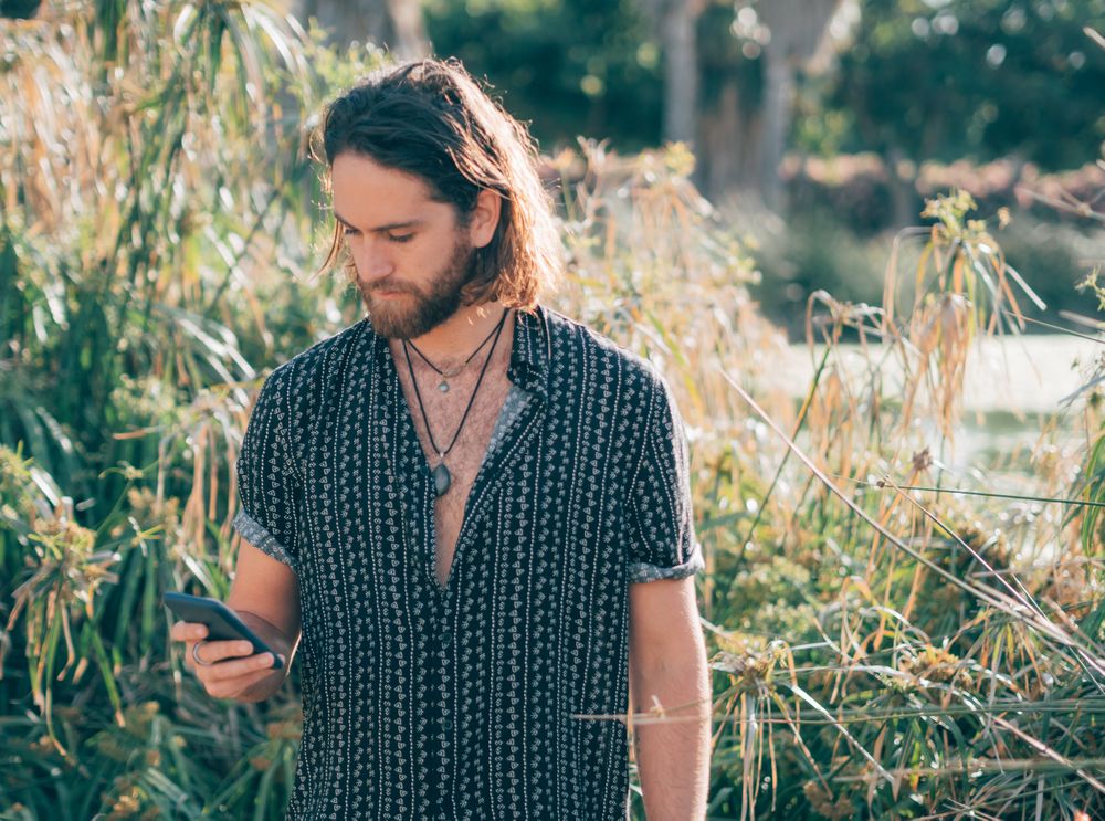 Young hipster man texting in jungle