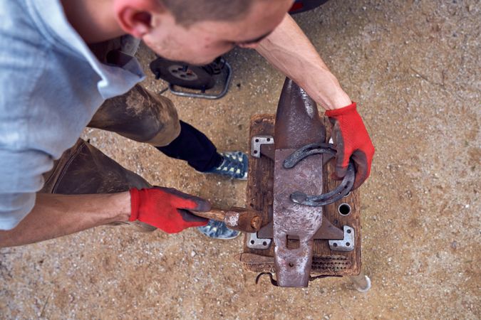 Blacksmith working on the anvil changing the horseshoe to a paw with tools