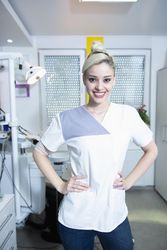 Happy dentist in her office with hands on hips