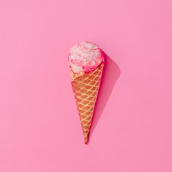 Waffle cone of pink ice cream on pink background