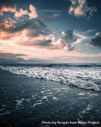 Waves of sea crashing on shore during cloudy sunset 5odB84
