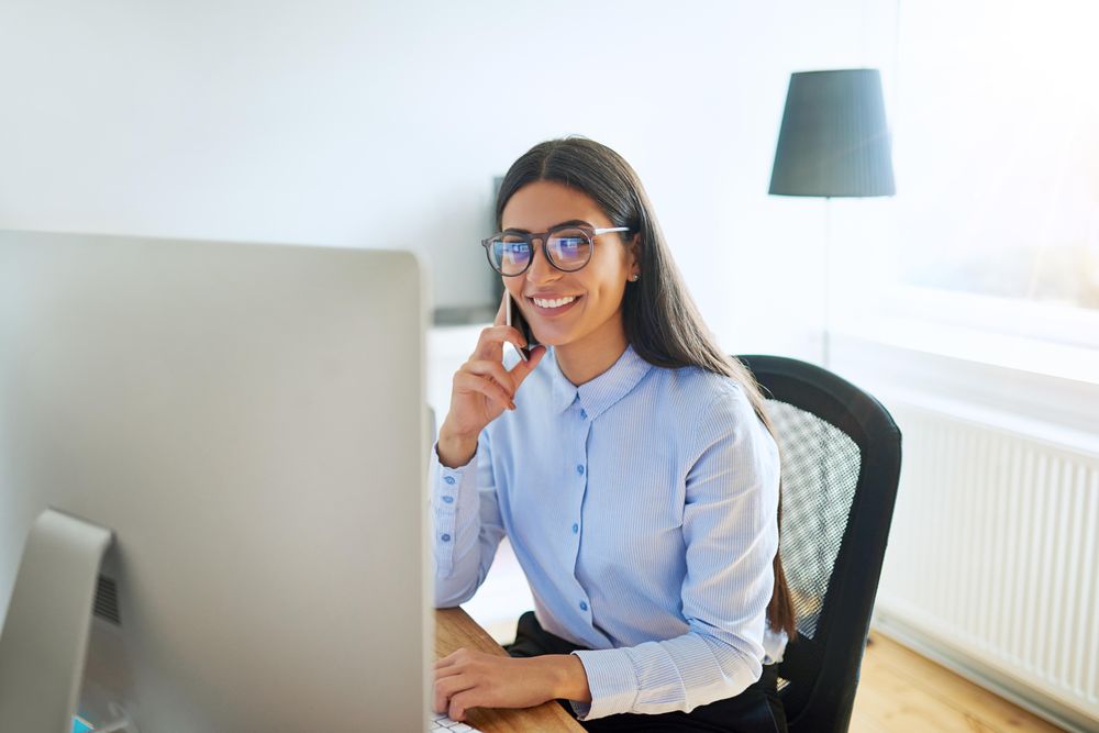 Smiling Arab female working at her desk taking a phone call