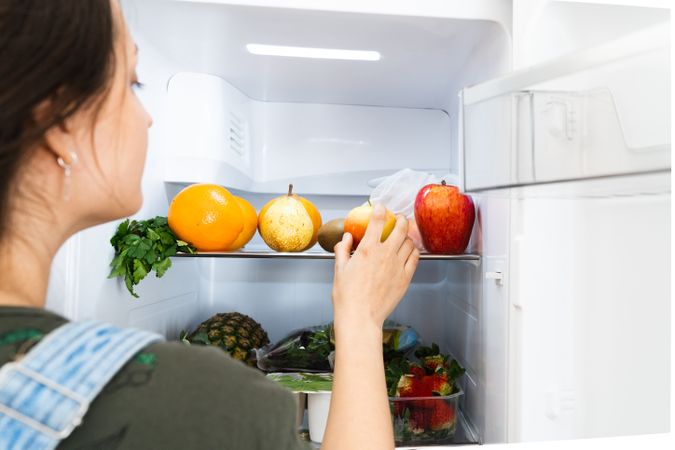 Crop woman taking fruit from fridge