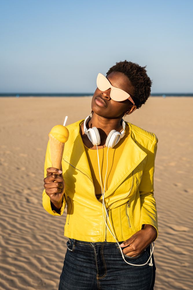 Cool female eating ice cream on beach