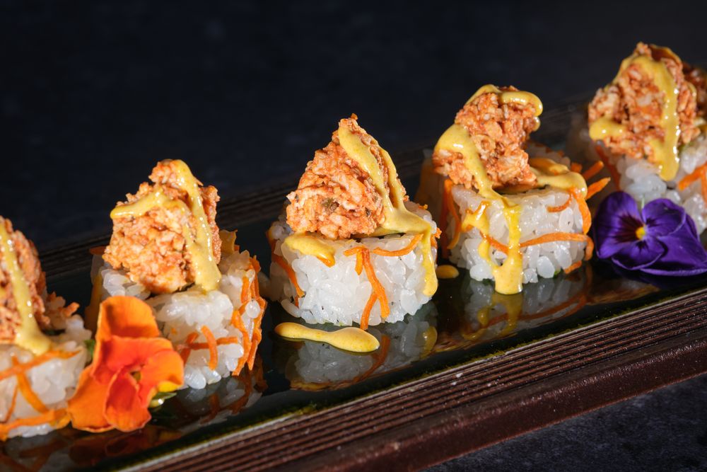 Appetizing sushi topped with salmon and fresh sauce served on wooden tray