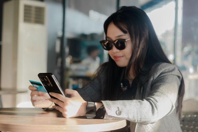 Asian young woman uses mobile banking and credit card, online shopping
