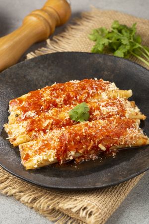 Pancakes stuffed with minced meat and topped with tomato sauce and grated cheese.
