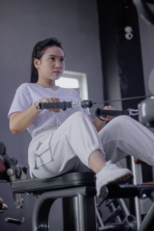 Concentrated woman using row machine in gym for back workout
