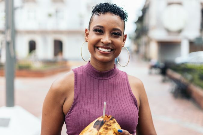 Latin American woman having fun in the city drinking coconuts