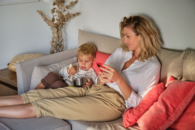 Mother and son resting on sofa together at home